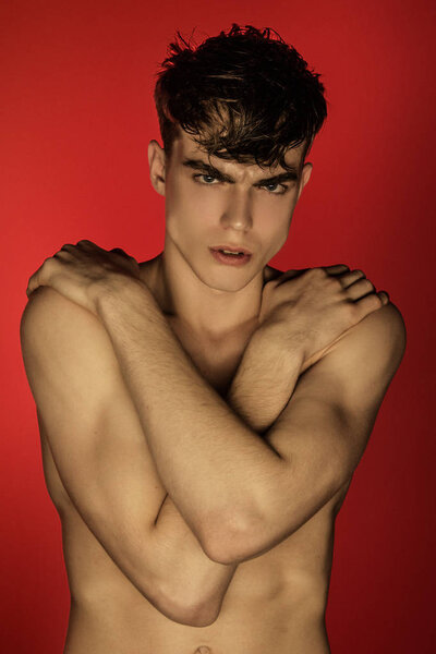 Muscle strong beautiful stripped male model in denim black jeans on red isolated font background