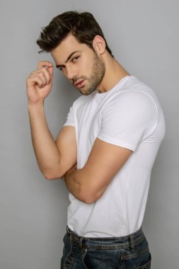 Kas gücü yüzlü güzel erkek model portresi kot pantolon içinde beyaz tişört gri izole font arka planda gölgeli