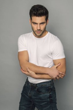 Kas gücü yüzlü güzel erkek model portresi kot pantolon içinde beyaz tişört gri izole font arka planda gölgeli