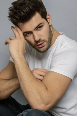 Kas gücü yüzlü güzel erkek model portresi kot pantolon içinde beyaz tişört gri izole font arka planda gölgeli
