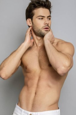 Kas gücü, güzel erkek model portresi, beyaz kot pantolon, gri izole font arka plan, gölge.