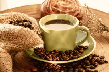 Kuru üzümlü tatlı çörek ve kahve çekirdekleri ile bir fincan kahve.