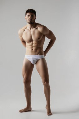 Gri izole font arka planda beyaz iç çamaşırlı güçlü erkek model.