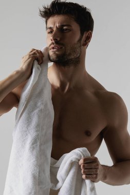 Gri izole font arka planında beyaz havlusu olan seksi kaslı kaslı adam.