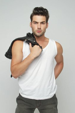 Kas gücü, kot pantolon ve deri ceketli, gri izole yazı tipi arka planda güzel, soyulmuş erkek model. 