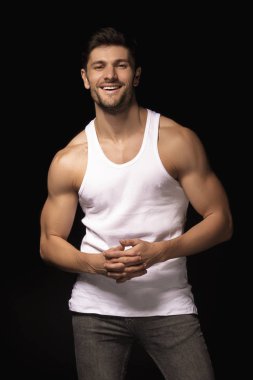 Muscle strong beautiful stripped male model with white shirt in denim gray jeans on black isolated font background