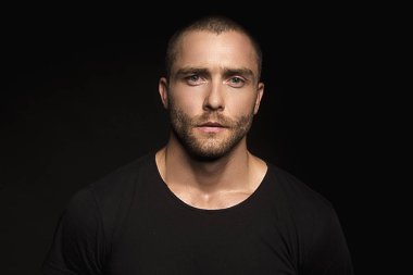 Siyah yalıtılmış yazı tipi arka planında kot kotlu siyah tişörtlü, kaslı, güzel, soyulmuş erkek model.