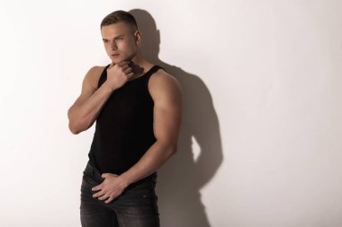 Kas gücü. Güzel, soyulmuş, siyah gömlekli, kot pantolonlu, beyaz, izole yazı tipi arka planda erkek model.