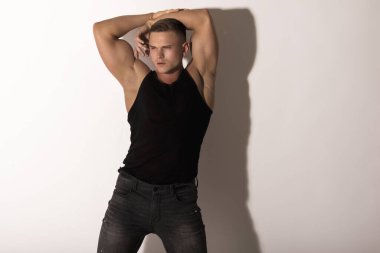 Kas gücü. Güzel, soyulmuş, siyah gömlekli, kot pantolonlu, beyaz, izole yazı tipi arka planda erkek model.