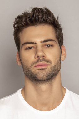 Kas gücü yüzlü güzel erkek model portresi kot pantolon içinde beyaz tişört gri izole font arka planda gölgeli