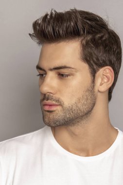 Kas gücü yüzlü güzel erkek model portresi kot pantolon içinde beyaz tişört gri izole font arka planda gölgeli