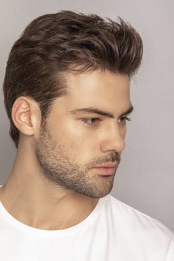 Kas gücü yüzlü güzel erkek model portresi kot pantolon içinde beyaz tişört gri izole font arka planda gölgeli