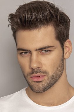 Kas gücü yüzlü güzel erkek model portresi kot pantolon içinde beyaz tişört gri izole font arka planda gölgeli