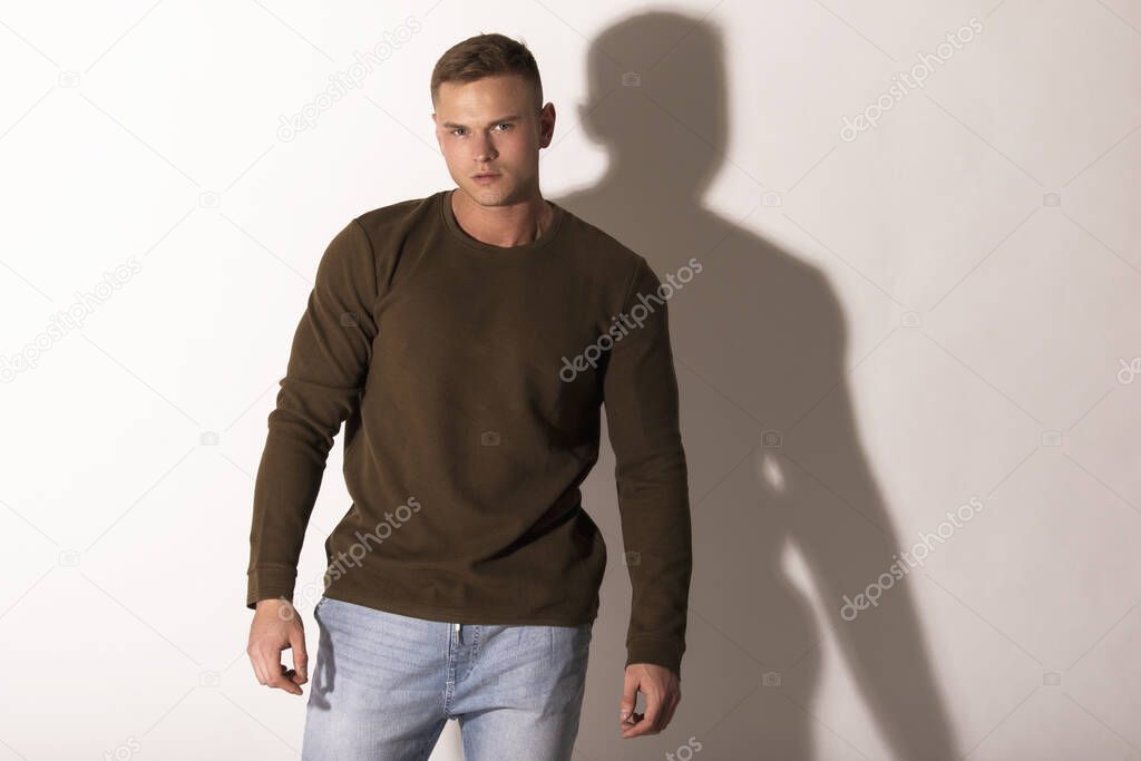 Muscle strong beautiful stripped male model in denim jeans with jumiper jumper on white isolated font background with shadow