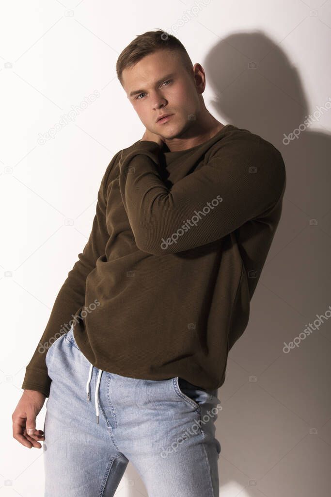 Muscle strong beautiful stripped male model in denim jeans with jumiper jumper on white isolated font background with shadow