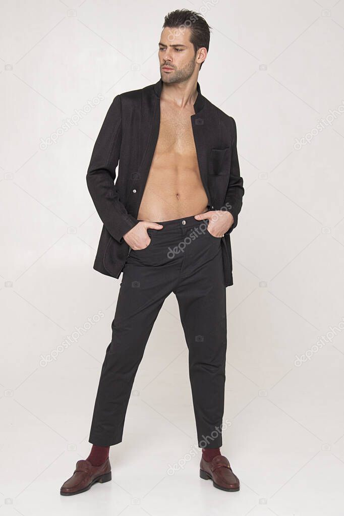 Muscle strong beautiful stripped male model in black toxedo and black trousers on grey isolated font background