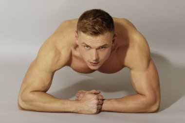 Beyaz iç çamaşırlı ve beyaz spor ayakkabılı güçlü kaslı erkek model gri izole yazı tipi arka planında egzersiz yaparken