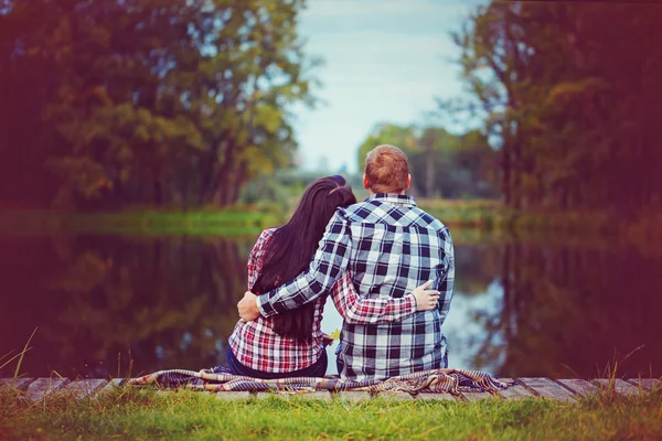 Couple amoureux dans le parc d'automne assis sur la plage, rivière ou lak — Photo