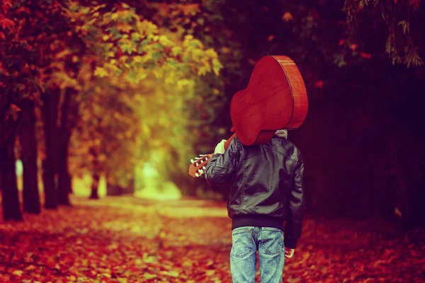 Sonbahar yolda yürürken gitar çocuk. Arkadan Görünüm. Tonda ıma