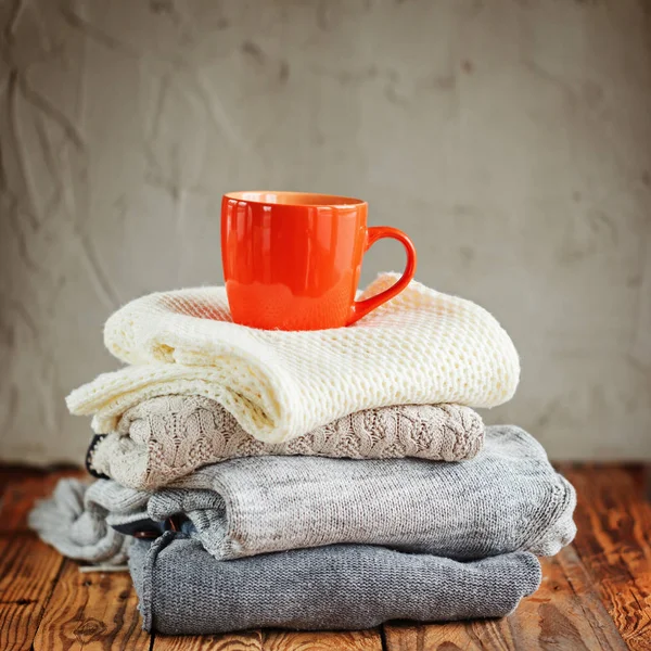 Kazak Closeup, örme kış giysileri ahşap arka plan üzerinde kırmızı kupa ile yığını.