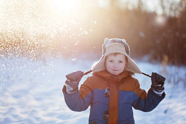 El niño pequeño de invierno jugando vomita nieve al aire libre durante las nevadas. Excursiones activas de ocio con niños en invierno en días fríos nevados — Foto de Stock