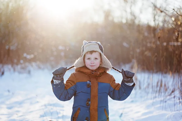 Winter little child playing throws up snow outdoors during snowfall. Active outoors leisure with children in winter on cold snowy days — Stock Photo, Image