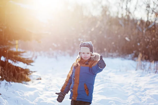 Winter little child playing throws up snow outdoors during snowfall. Active outoors leisure with children in winter on cold snowy days — Stock Photo, Image