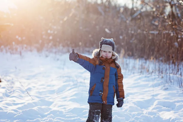 Zimní malé dítě hraje hází nahoru sníh venku během sněžení. Aktivní outoors volný čas s dětmi v zimě studené zasněžené dny Royalty Free Stock Fotografie