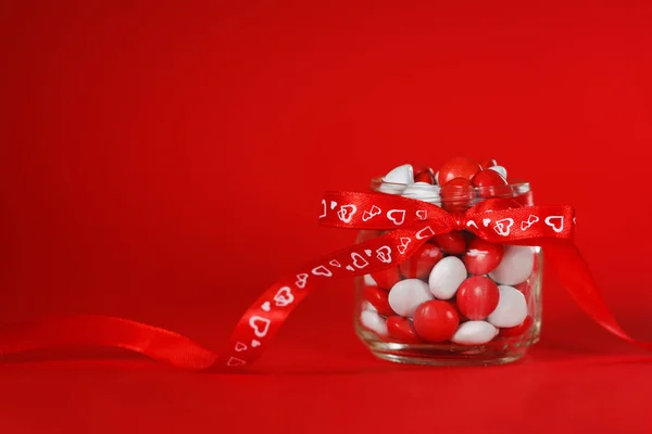 カラフルなキャンディの瓶赤弓心の背景に飾られています。バレンタインの日の概念 — ストック写真