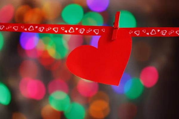 红纸心挂在彩色背景上的红丝带。概念的情人节 — 图库照片