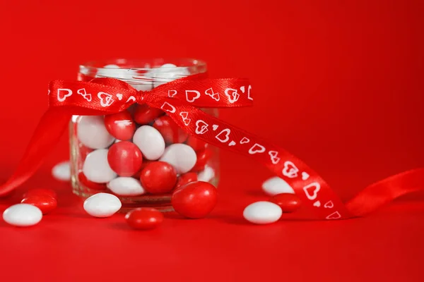 Colorful candy jar decorated with a red bow  hearts on  backgrou — Stock Photo, Image
