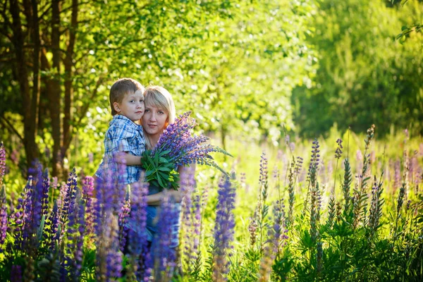Matka i jej synka z bukietem kwiatów w dniu wiosny. Szczęśliwa rodzina Mama i dziecko przytulanie — Zdjęcie stockowe