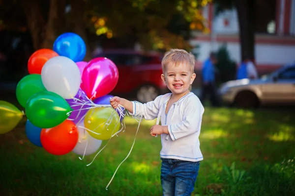 Happy child with colorful toy balloons outdoors. Smiling kid having fun in summer sunny day — Stock Photo, Image