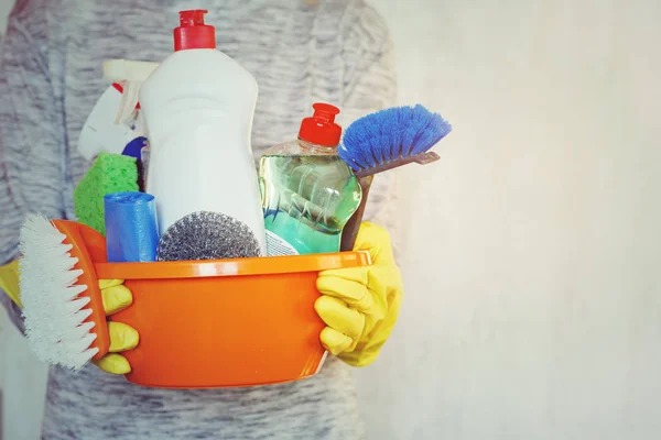Mujer manos sosteniendo bañera con suministros de limpieza . — Foto de Stock