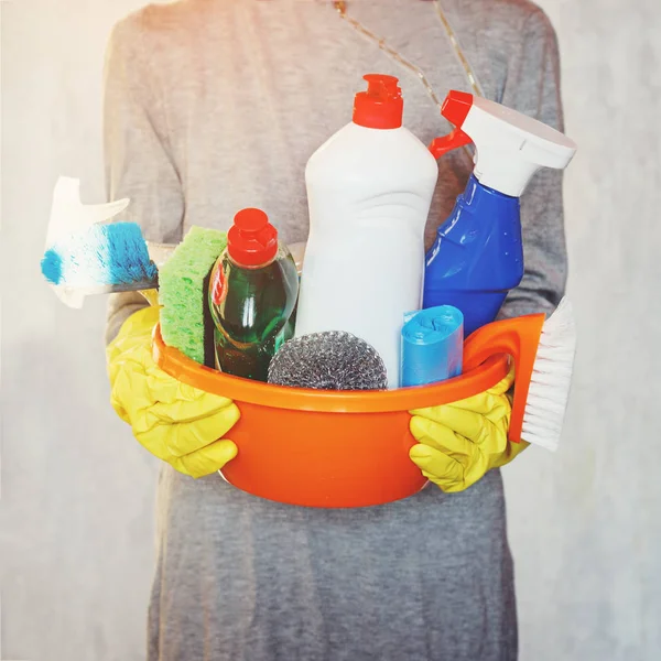 Mujer manos sosteniendo bañera con suministros de limpieza . — Foto de Stock