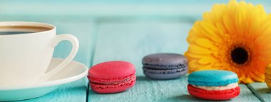 Kahve ya da çay sarı çiçek ve mavi arka plan üzerinde macaroons