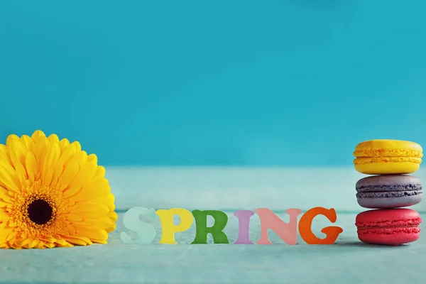 Palabra de papel de primavera con gerberas amarillas y macarrones sobre fondo azul. Hola primavera. Fondo de pantalla de primavera — Foto de Stock