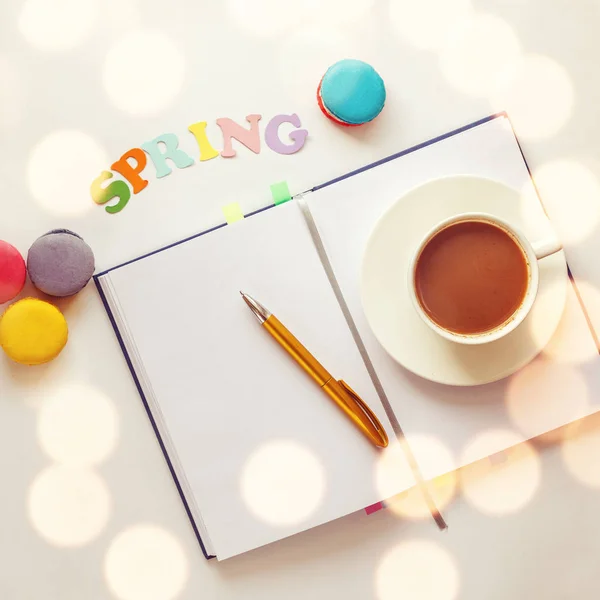 春の単語のビュー i.mage をトップ、空白のノートブックとカラフルなマカロンと紅茶やコーヒーのカップを開く — ストック写真
