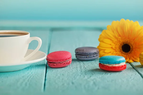 Tasse Kaffee oder Tee mit gelben Blüten und Makronen auf blauem Hintergrund. — Stockfoto