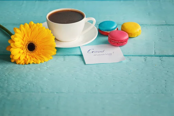 Tasse Kaffee oder Tee mit gelben Blüten und Makronen auf blauem Hintergrund — Stockfoto