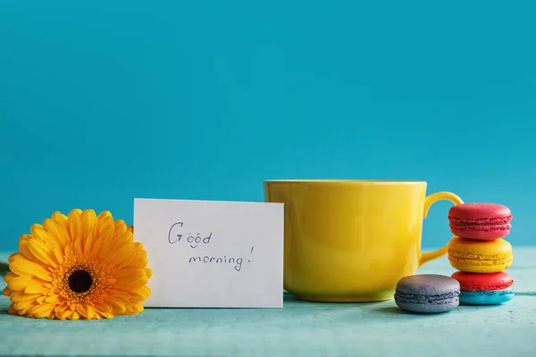 Große Tasse Tee mit weißer Blume und Makronen mit Leerzeichen auf blauem Hintergrund — Stockfoto