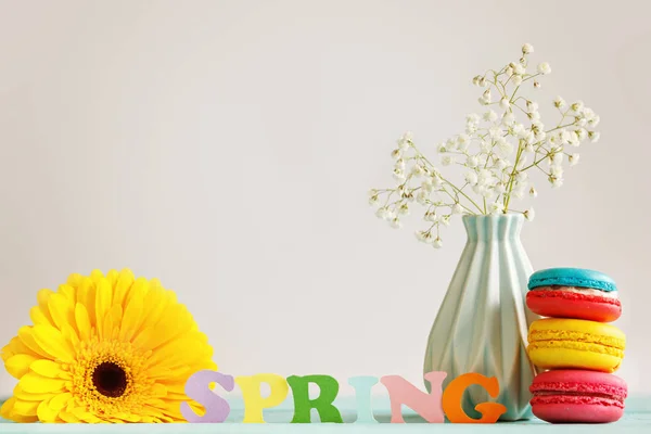 Frühlingspapier Wort mit gelben Blume und Macfroons auf dem Hintergrund. Hallo Frühling. FrühlingTapete. — Stockfoto