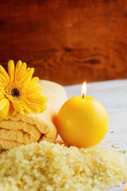 Spa sarı ürünleri ayarlama. Deniz tuzu, havlu ve koyu ahşap zemin üzerine mumlar