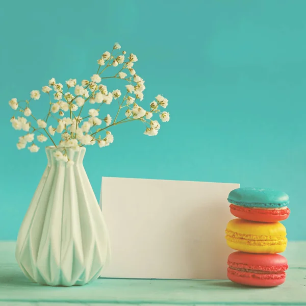 Prázdný papír karta s šálkem čaje andvase v květu a macaroons pro ženu den — Stock fotografie