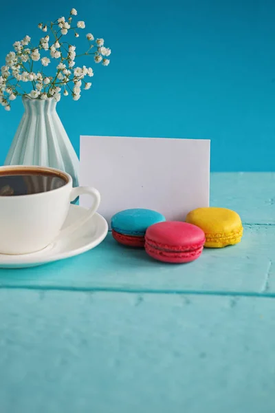 Пустая бумажная карточка с чашкой чая и вазой в цветах и макаронах на женский день — стоковое фото