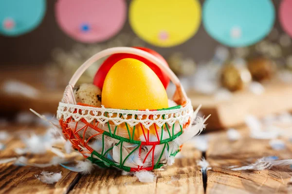 Composição de Páscoa de ovos coloridos de Páscoa na cesta e com guirlanda de coelho no fundo de madeira . — Fotografia de Stock