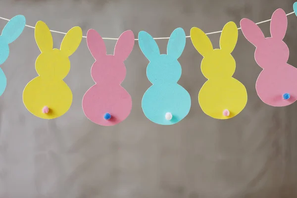 Гирлянда с красочными бумажными кроликами на сером фоне. Концепция пасхального кролика — стоковое фото