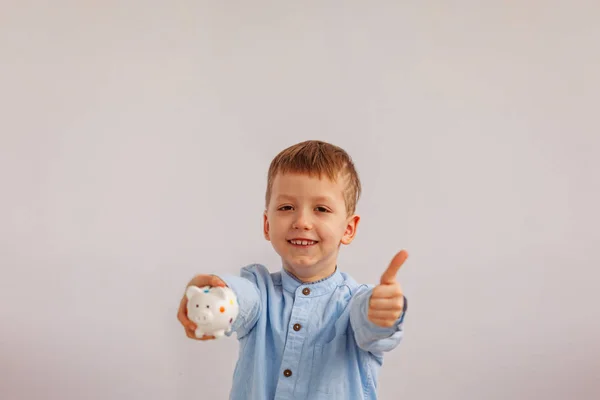 Schattige kleine jongen bezit is van een spaarvarken of spaarpot. — Stockfoto