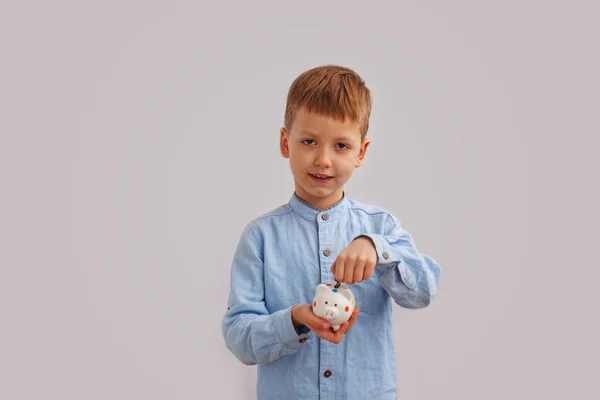 Child's hand put into white piggybank money coins. — Stock Photo, Image