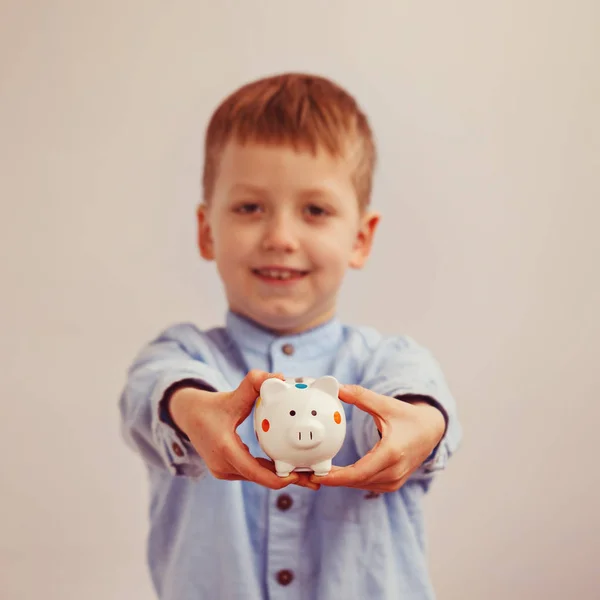 Lindo niño sosteniendo una alcancía, enfoque suave en la caja de dinero —  Fotos de Stock